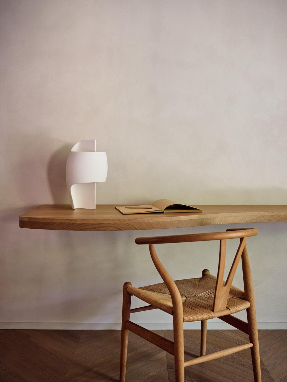 Wooden wall shelf with a sculptural lamp, book and chair