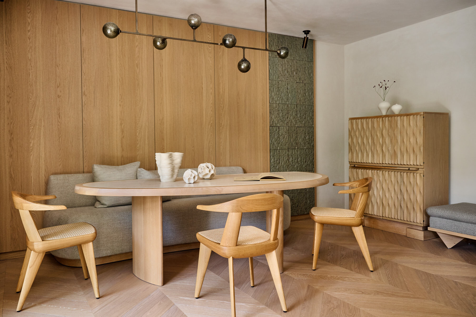 Dining area with an oval table, oak panelling and a brass pendant light